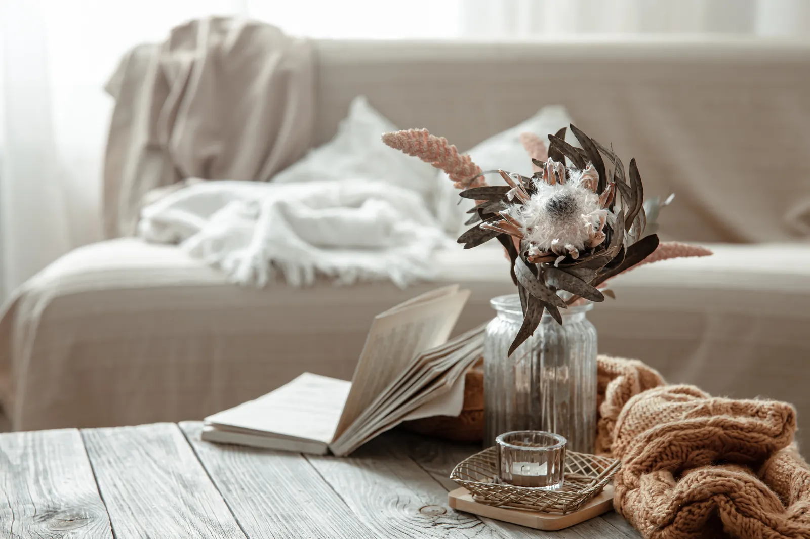 Cosy still life with a book, dried flowers and soft textiles